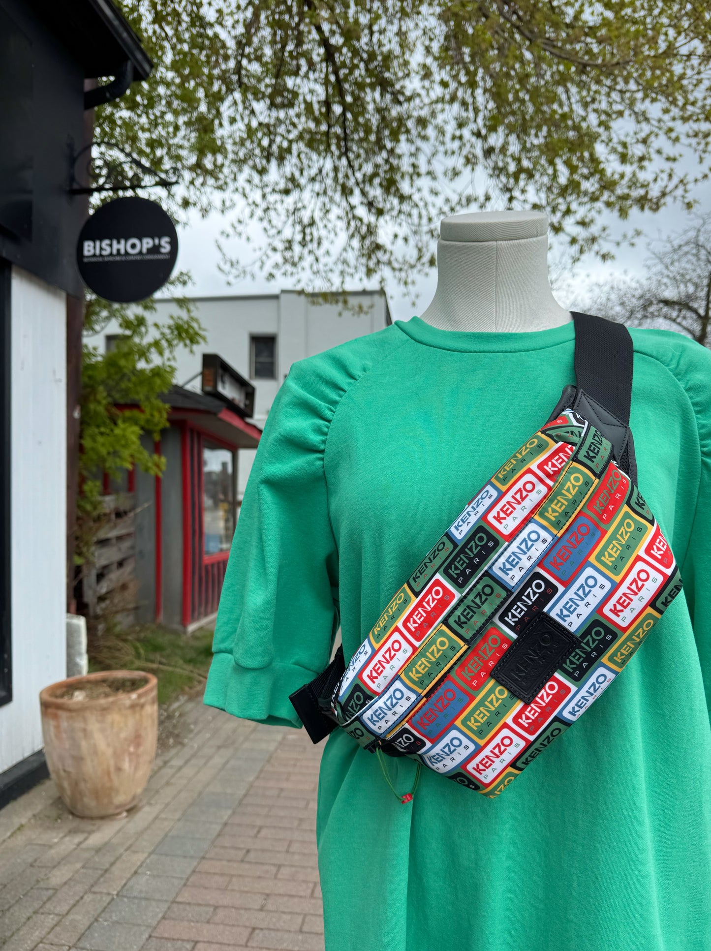 Person wearing a green dress with a colorful Kenzo Belt bag outdoors.