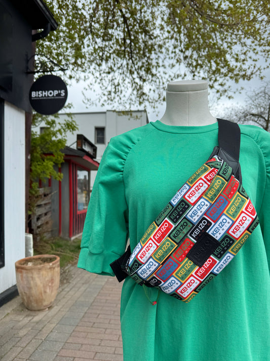 Person wearing a green dress with a colorful Kenzo Belt bag outdoors.