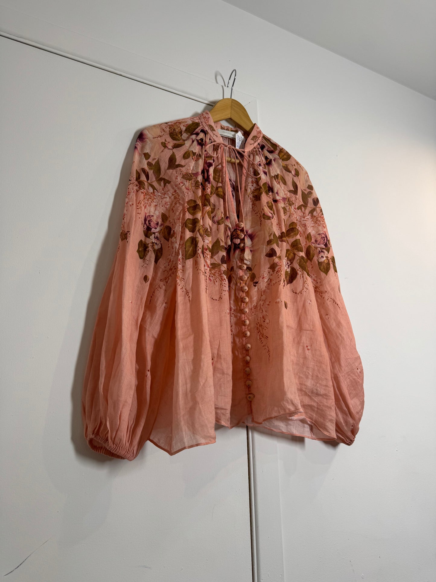 Pink floral Zimmermann blouse hanging on a white wall