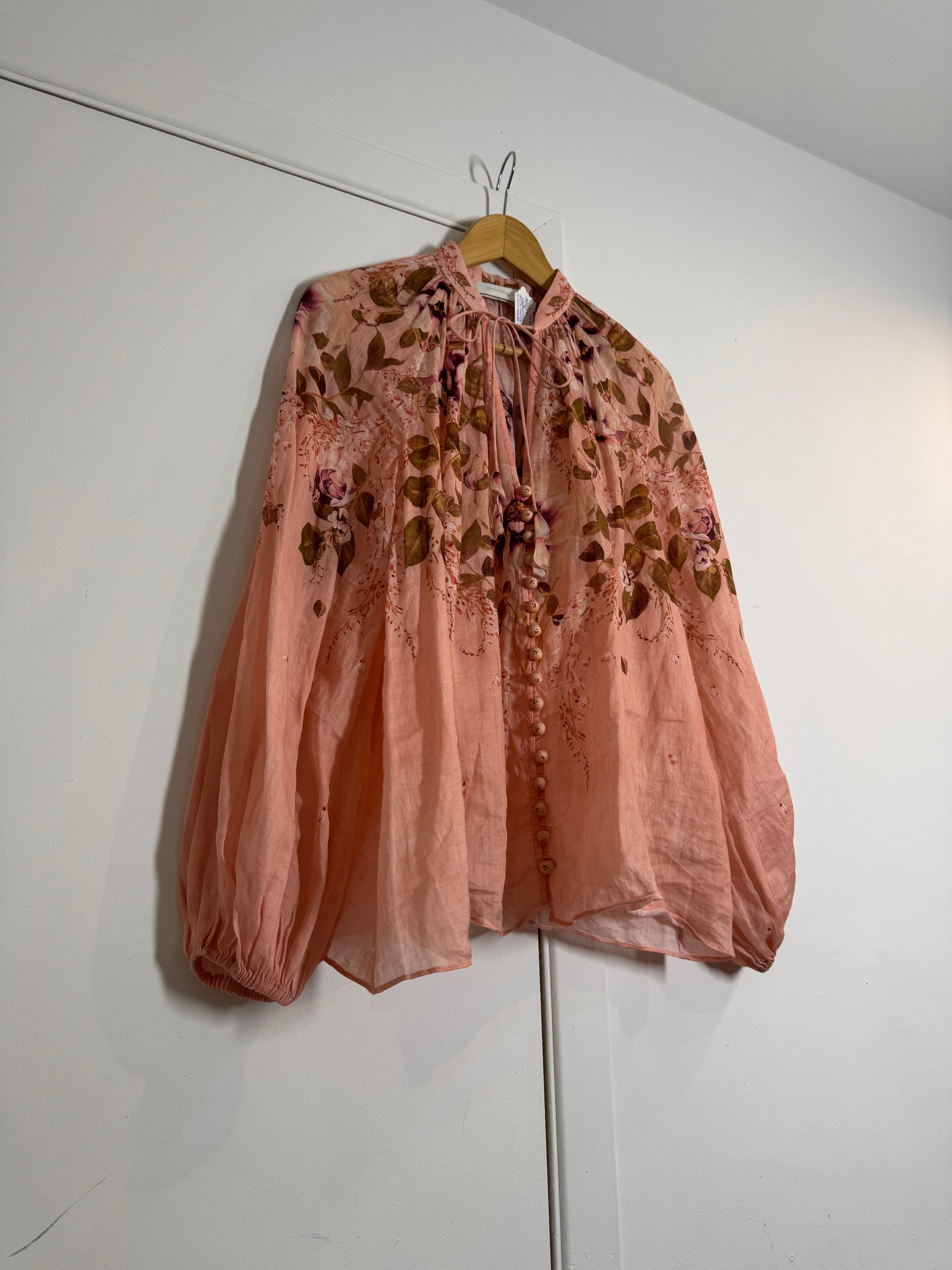 Pink floral Zimmermann blouse hanging on a white wall